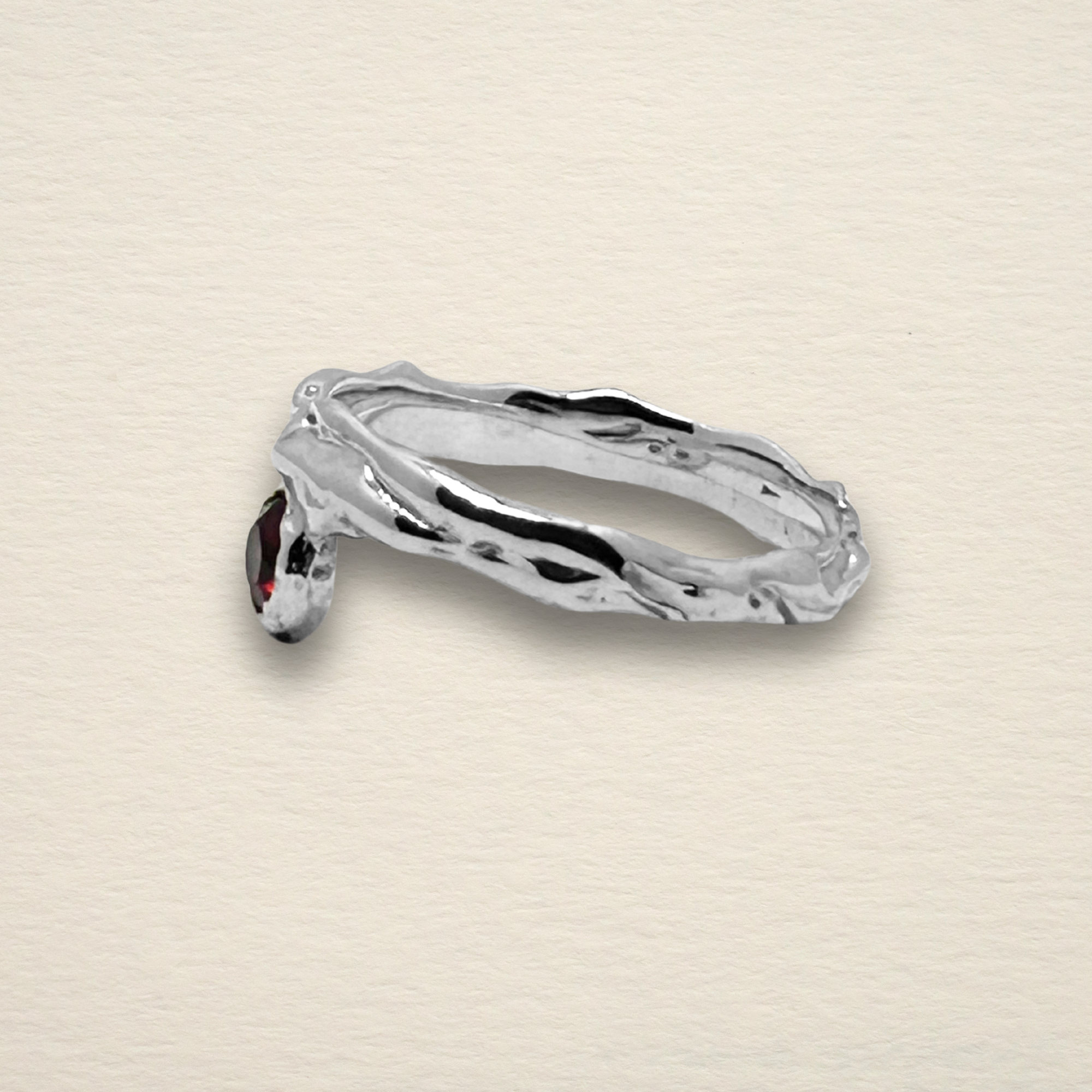 Profile view of the Archive Series Rhodolite Garnet ring, highlighting the asymmetrical, offset design and the fluid, raw-edged metalwork of the sculpted band.