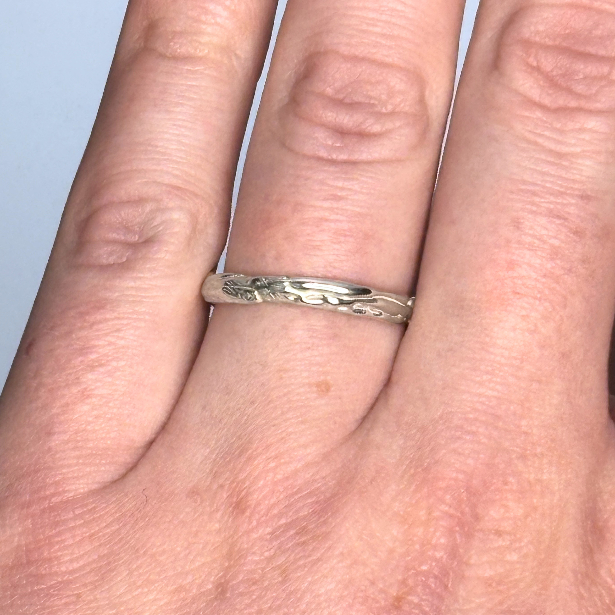 The Archive Series Sculpted Band worn as a singular, refined artifact, highlighting the intricate, hand-sculpted organic texture of the recycled sterling silver band on the hand.