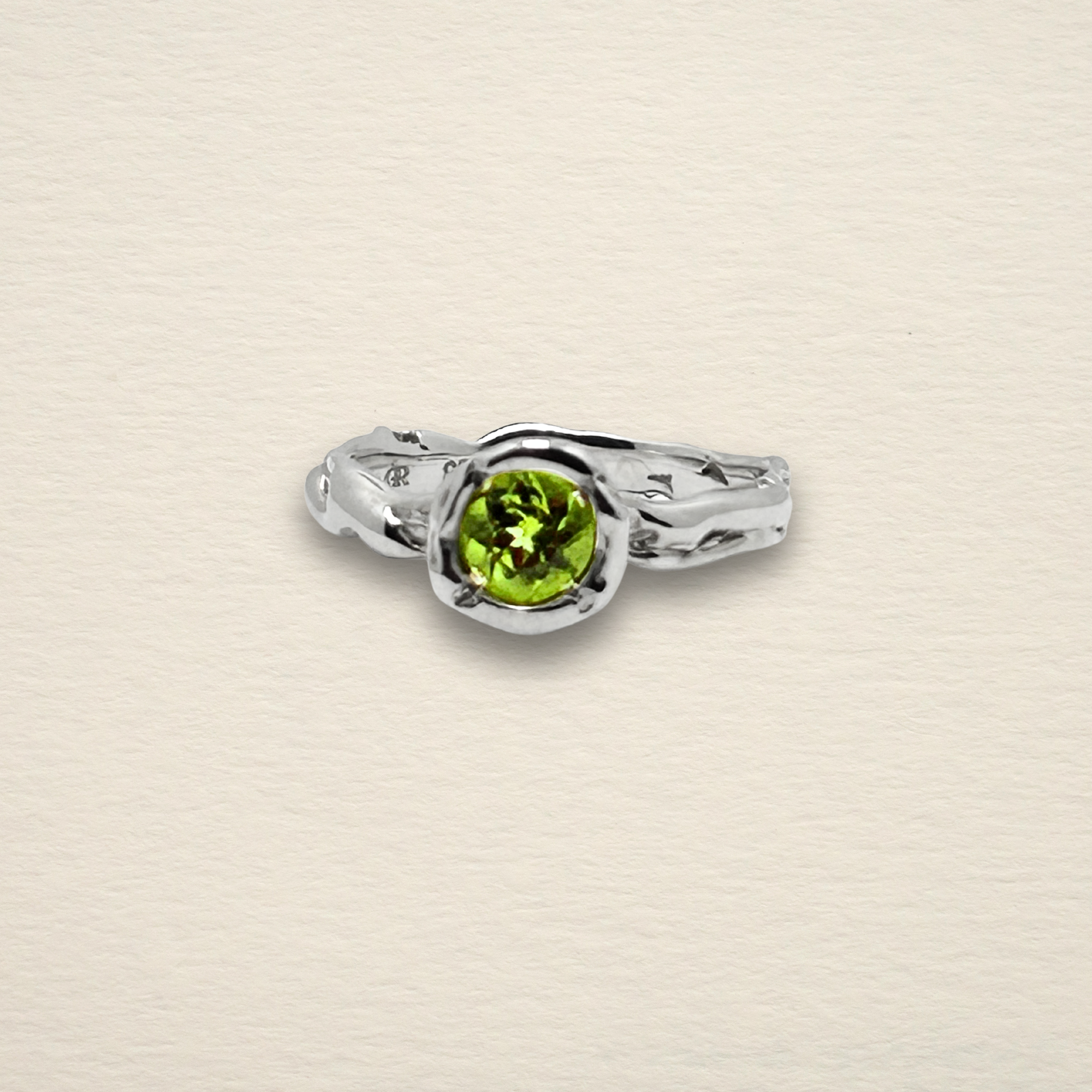 Close-up detail of the Archive Series Peridot Solitaire, showcasing the fluid, organic texture of the hand-sculpted sterling silver band and the precision of the burnished bezel setting.