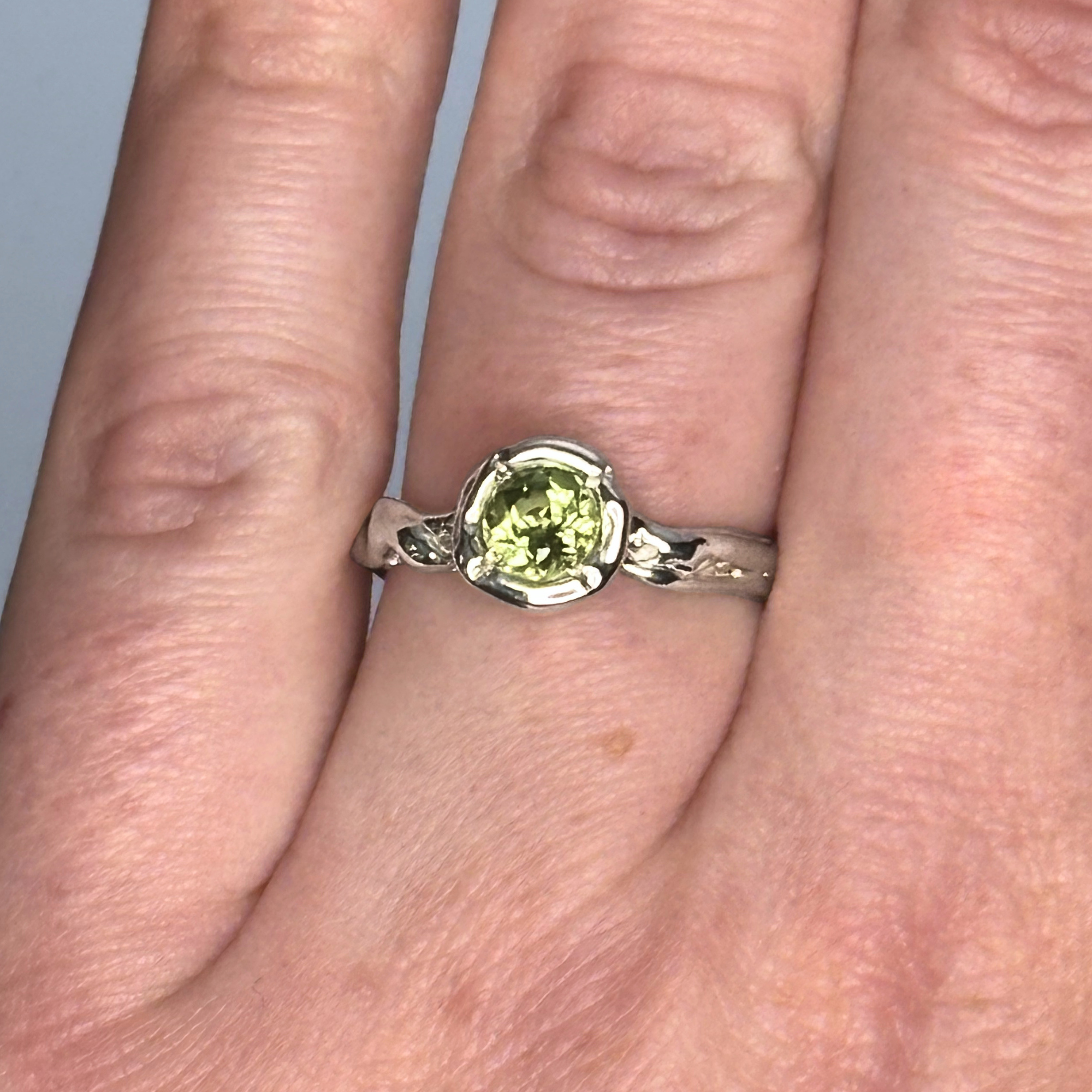 The Archive Series Peridot Solitaire worn as a bespoke, sovereign artifact, emphasizing the intentional silhouette and tactile master goldsmithing quality of the piece on the hand.
