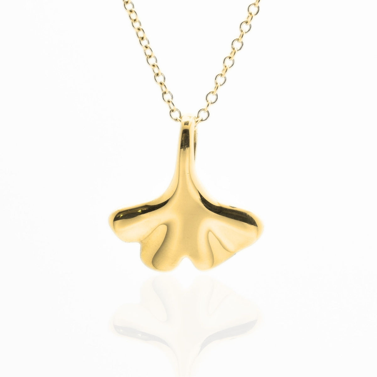 Direct front view with reflection of the Botanical Ginkgo Leaf Pendant 14mm petite in 18k yellow gold, emphasizing the tactile volume and fine jewelry craftsmanship of Gina Rose Atelier.