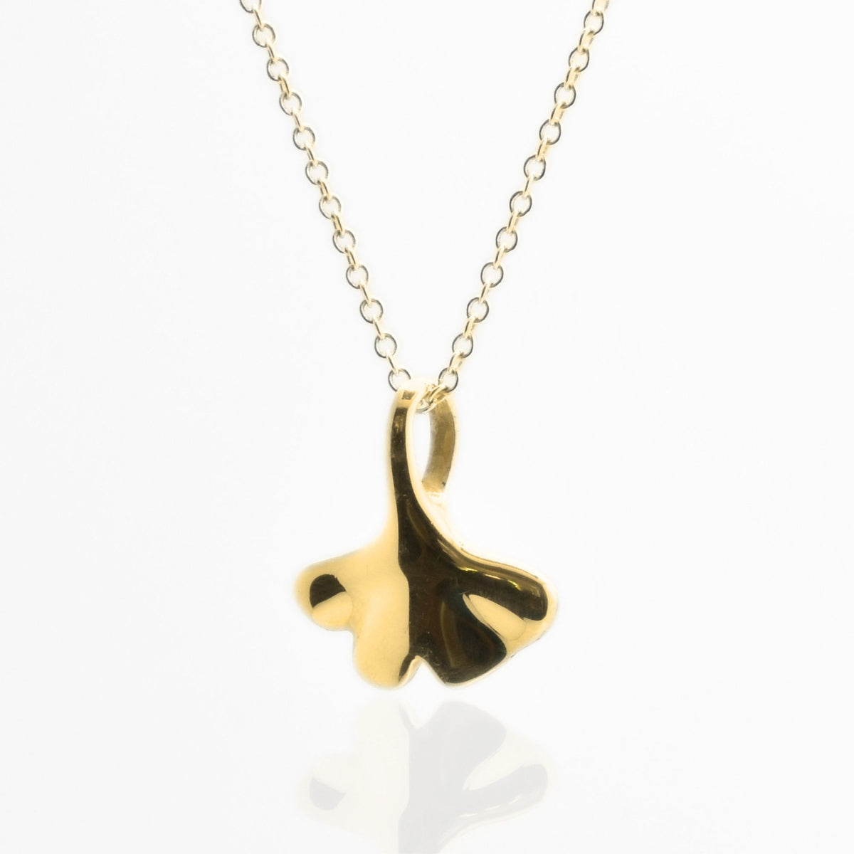 Studio reflection view of the Botanical Ginkgo Leaf Pendant 14mm petite in solid 18k yellow gold, highlighting the hand-finished fan-shaped architecture from Gina Rose Atelier.