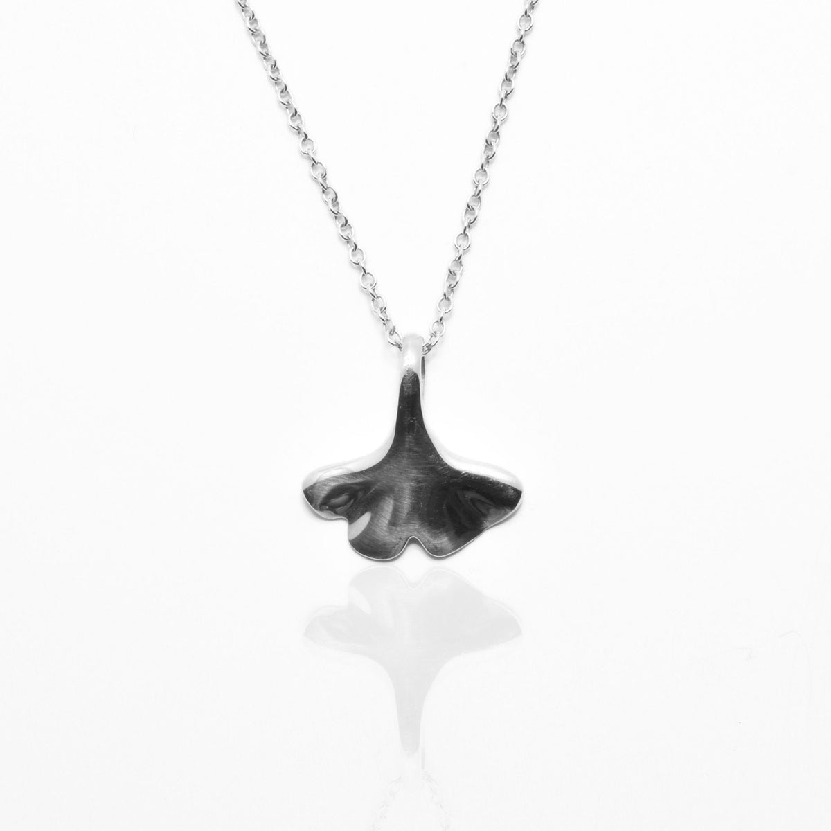 The Botanical Ginkgo Leaf Pendant in 14mm petite scale crafted in solid sterling silver by Gina Rose Atelier, shown with a mirror studio reflection on a custom silver chain.