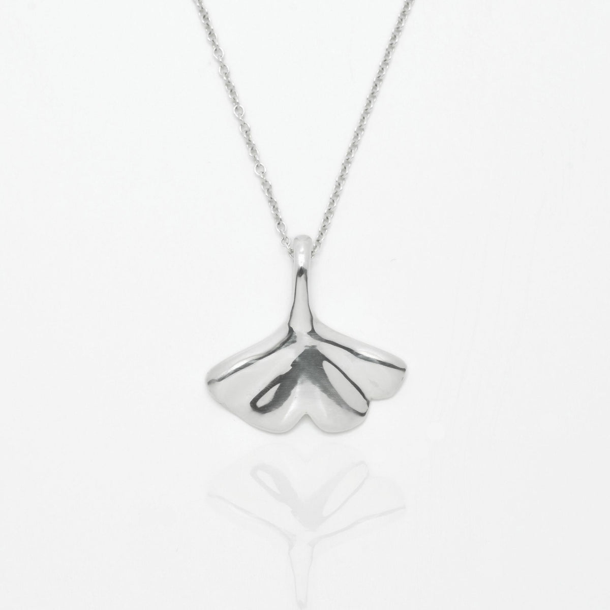 The Botanical Ginkgo Leaf Pendant in 20mm grande scale crafted in solid sterling silver by Gina Rose Atelier, shown with a mirror studio reflection on a custom silver chain.