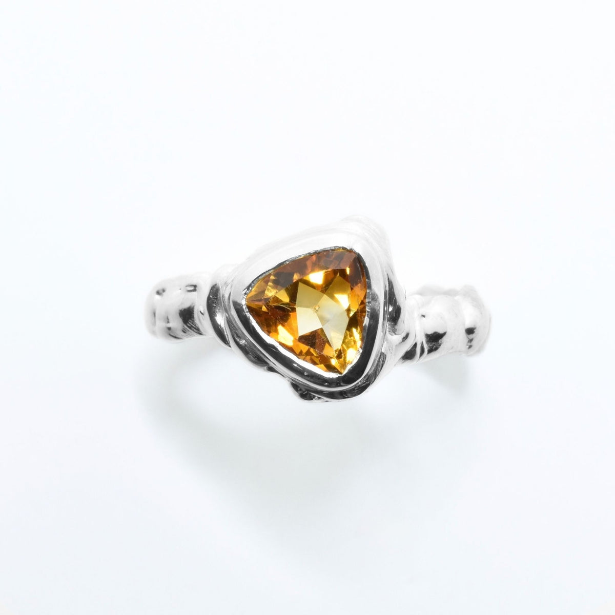 Direct studio front view of the Trillion Citrine Solitaire ring from the Archive Series in solid sterling silver, emphasizing tactile texture and fine jewelry craftsmanship.